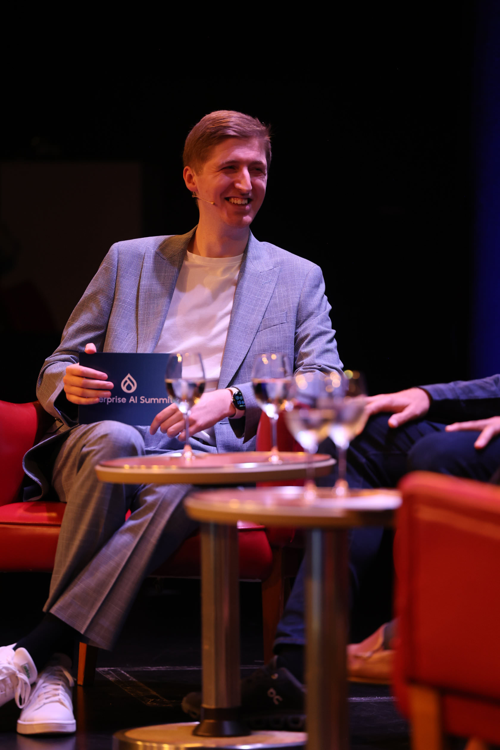 A smiling panellist holding an Enterprise AI Summit card on stage